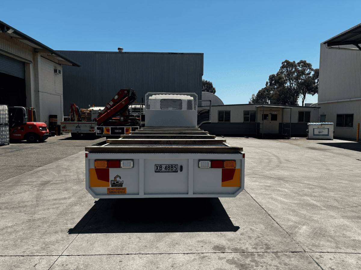 Customised FCM flatbed tray seen from rear, showing timber battens, licence plate and visible safety signage.