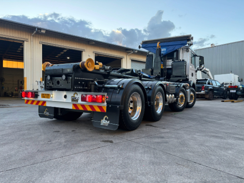 Rear view of truck fitted with FMC hooklift system, featuring hydraulic lift arms and multi-axle support for heavy loads.