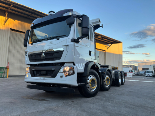 CNHTC T5G 330 cab chassis with FMC hooklift system installed (not visible), viewed from front angle in industrial setting.