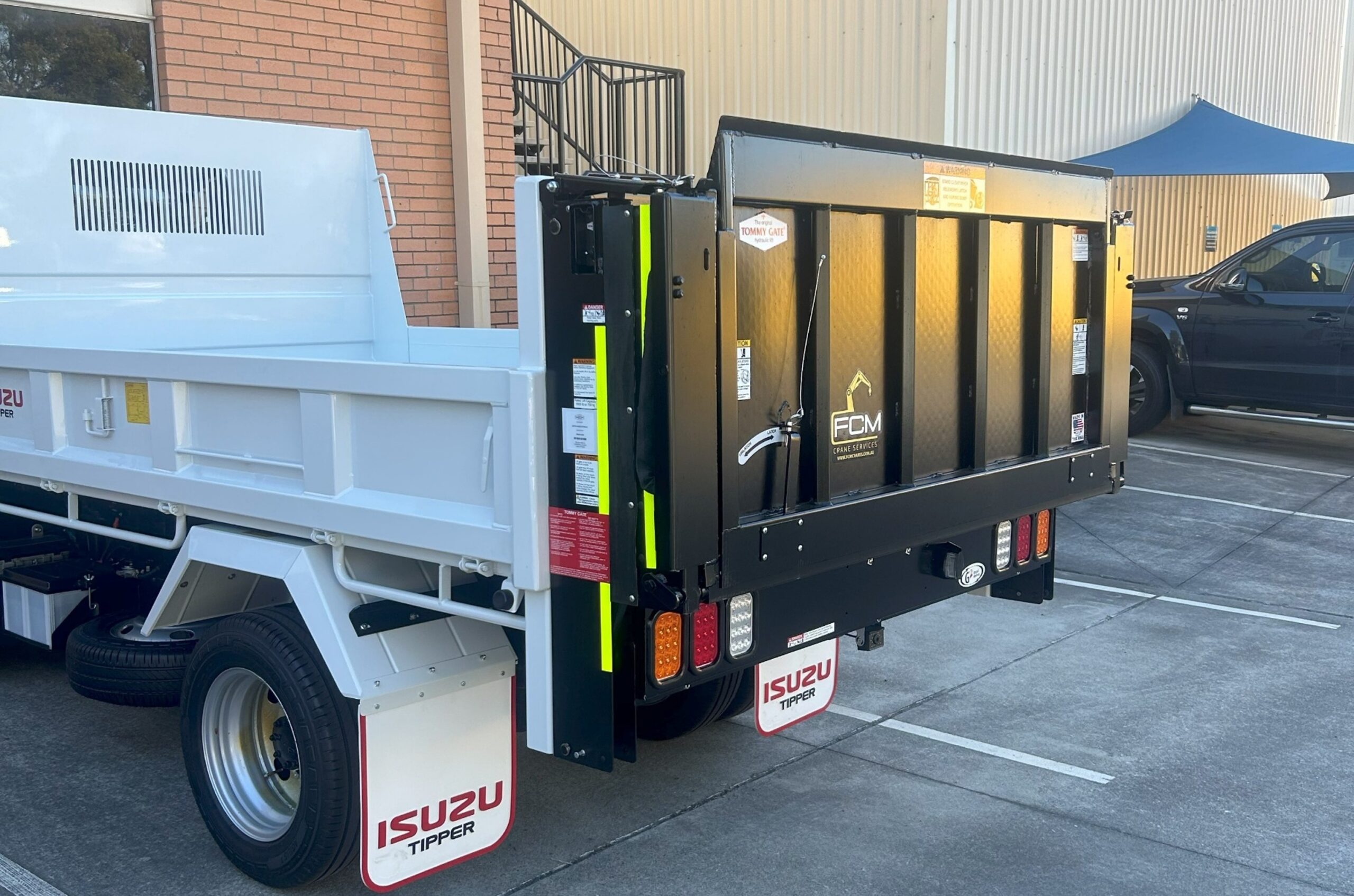 truck equipped with an FCM tailgate/liftgate, shown from rear side angle outside a building.
